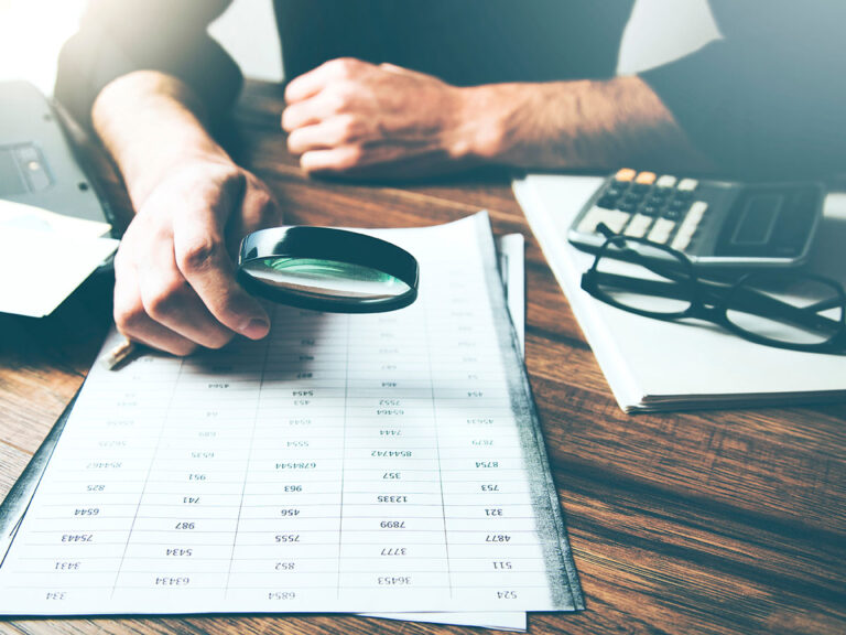 Man looking at papers through a magnifying class