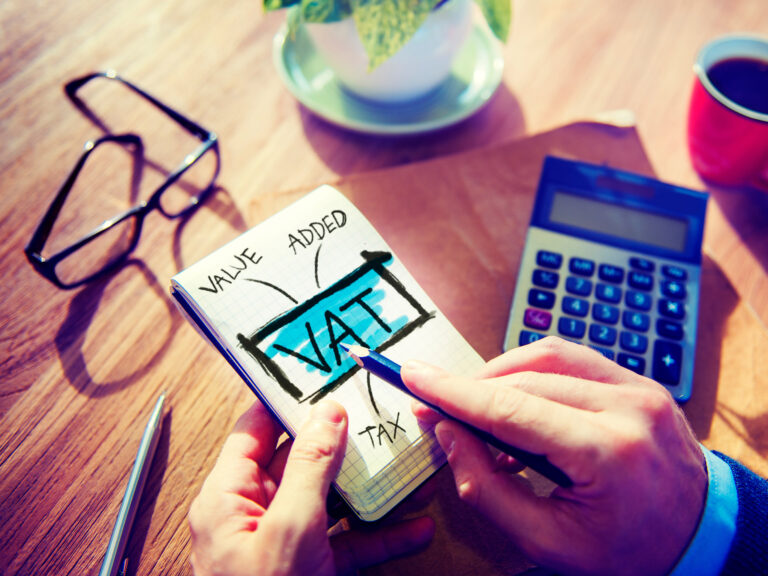 Hands holding notebook that says VAT