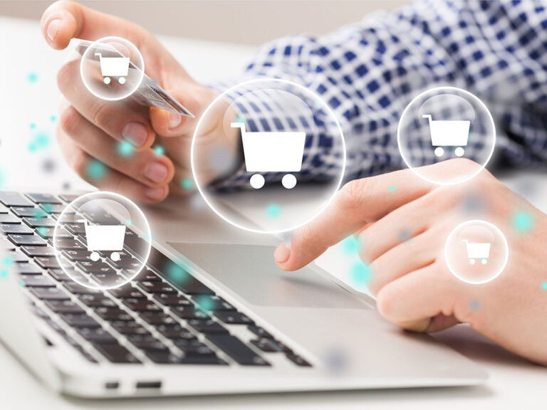 Man at laptop holding a credit card superimposed with shopping cart icons