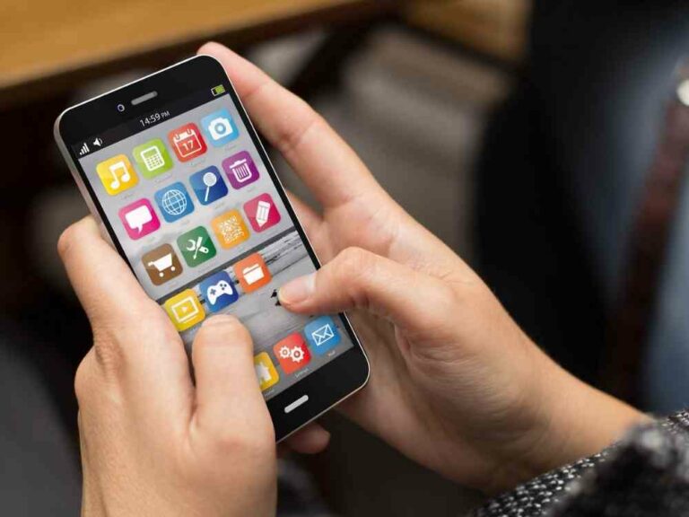 Hands holding a mobile phone showing app icons