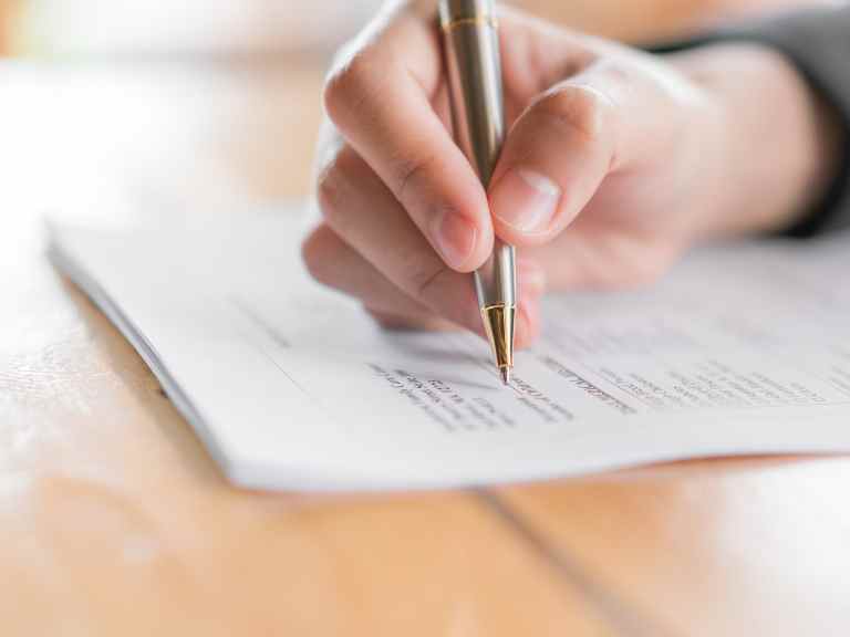 Hand holding pen to complete form