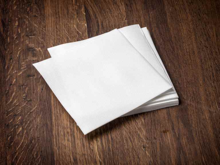 Stack of white paper napkins on wood table