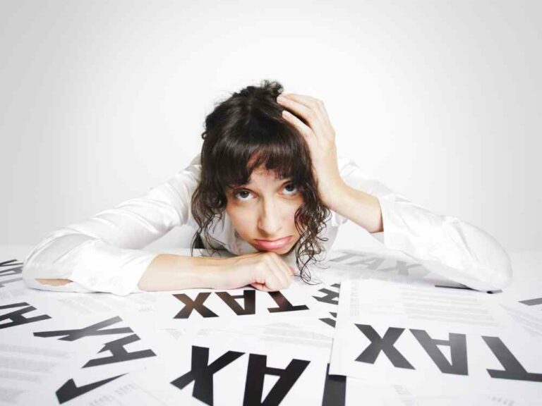 Stressed woman leaning over papers that say the word tax on them