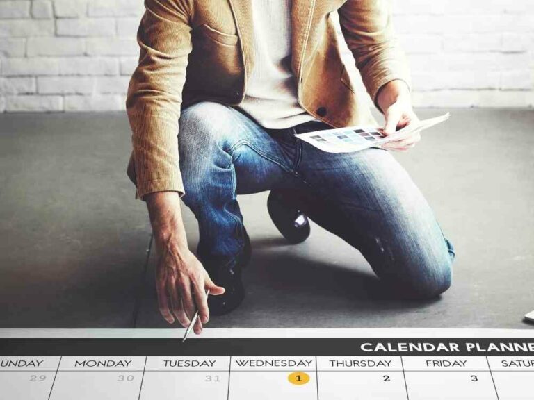 Man squatting in front of large calendar on the floor